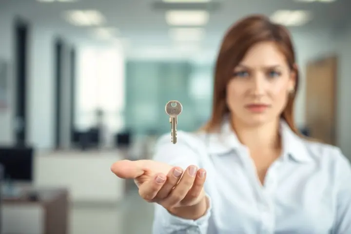 Verlust beruflicher Schlüssel: Woman holding a key, looking concerned about loss.