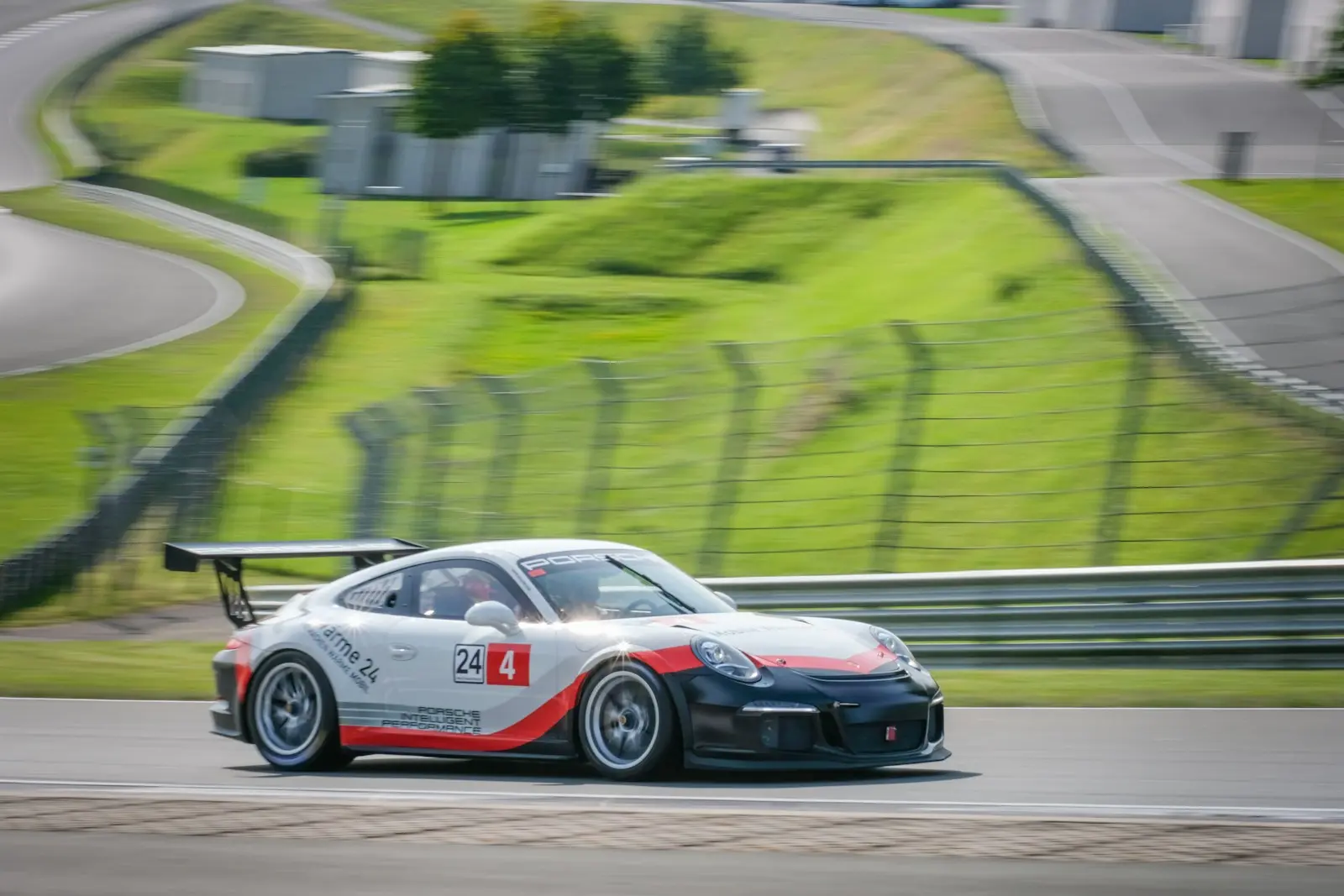 A car driving on a race track with grass in the background